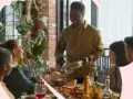 Un homme sert des plats à des amis lors d'un repas convivial. C'est un moment de partage, un temps de pause entre deux services restauration, où la joie règne.