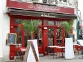 Le Café Gourmand, un restaurant aux noms originaux, invite à la dégustation avec sa façade rouge vif et ses palmiers.