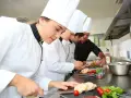Des chefs apprennent à travailler dans un restaurant, préparant des plats avec soin.