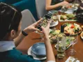 Une food influencer capture un repas coloré avec son téléphone, prête à partager ses découvertes culinaires.