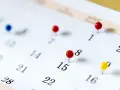 Un calendrier avec des punaises marque des dates importantes. Il est difficile de déterminer quels sont les 6 jours fériés garantis HCR sans plus de contexte.