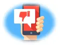 Main d'une personne tenant un smartphone affichant un pouce vers le bas dans une bulle de dialogue. Un mauvais avis sur un achat.