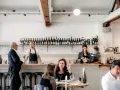 Un bar de restaurant animé avec un personnel attentif, des bouteilles de vin alignées et des clients profitant de l'ambiance. La gestion du restaurant assure un service fluide.