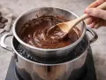 Du chocolat fondant est mélangé avec une cuillère en bois, posé sur une casserole d'eau bouillante pour faire chauffer au bain marie.