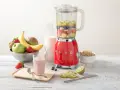 Un blender rouge SMEG, rempli de fruits, prêt à préparer un smoothie. Il montre à quoi sert un blender : mixer des ingrédients pour des boissons saines et délicieuses.