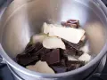 Morceaux de chocolat noir et de beurre dans un bol en métal, prêts pour une cuisson au bain-marie au four.