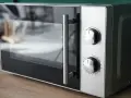 Gros plan sur un four micro-ondes avec deux boutons de réglage. Il est prêt à cuire, réchauffer ou décongeler, offrant le mode convection micro onde.