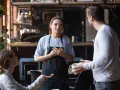 Serveuse attentive face à une cliente mécontente exprimant sa frustration. La serveuse écoute avec empathie.