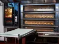Four à convection professionnel avec plusieurs étages de cuisson. Des pains dorés et des croissants attendent d'être dégustés.