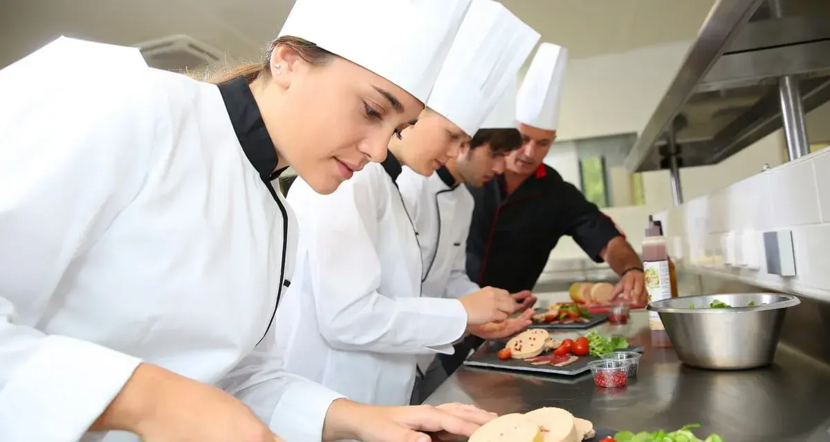 Des chefs apprennent à travailler dans un restaurant, préparant des plats avec soin.