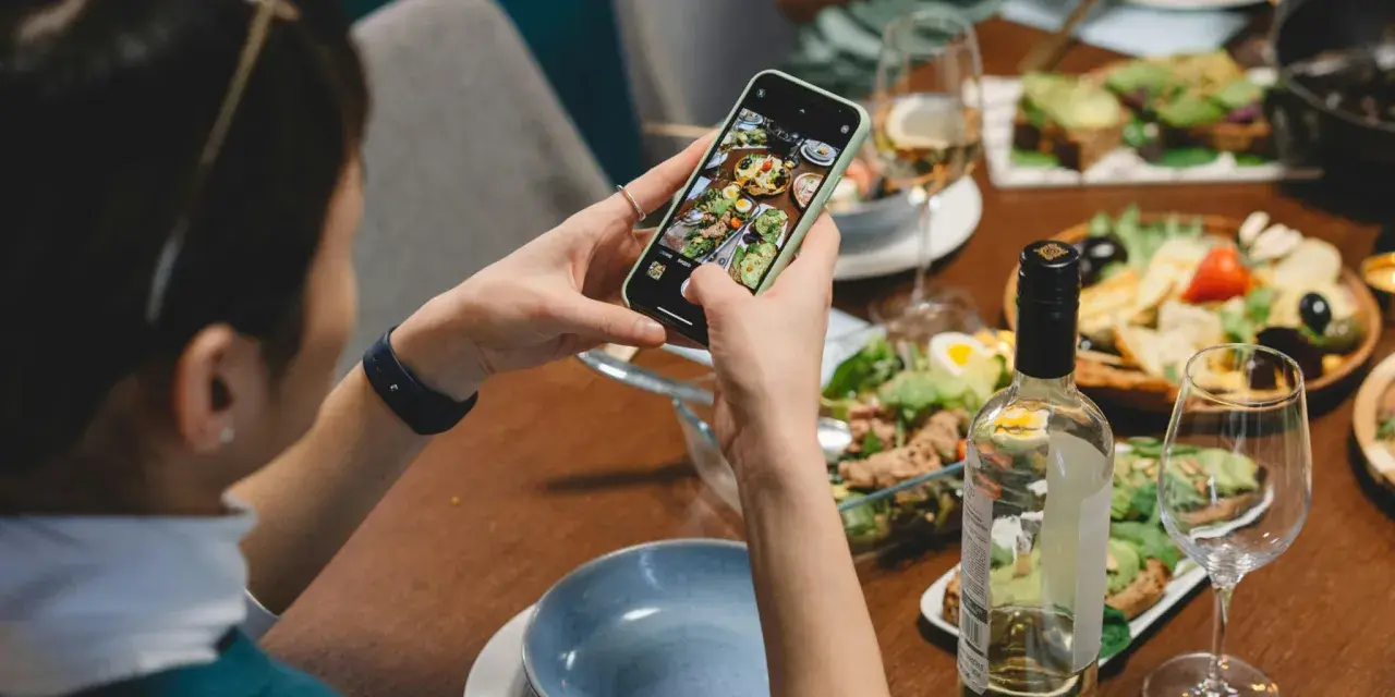 Une food influencer capture un repas coloré avec son téléphone, prête à partager ses découvertes culinaires.