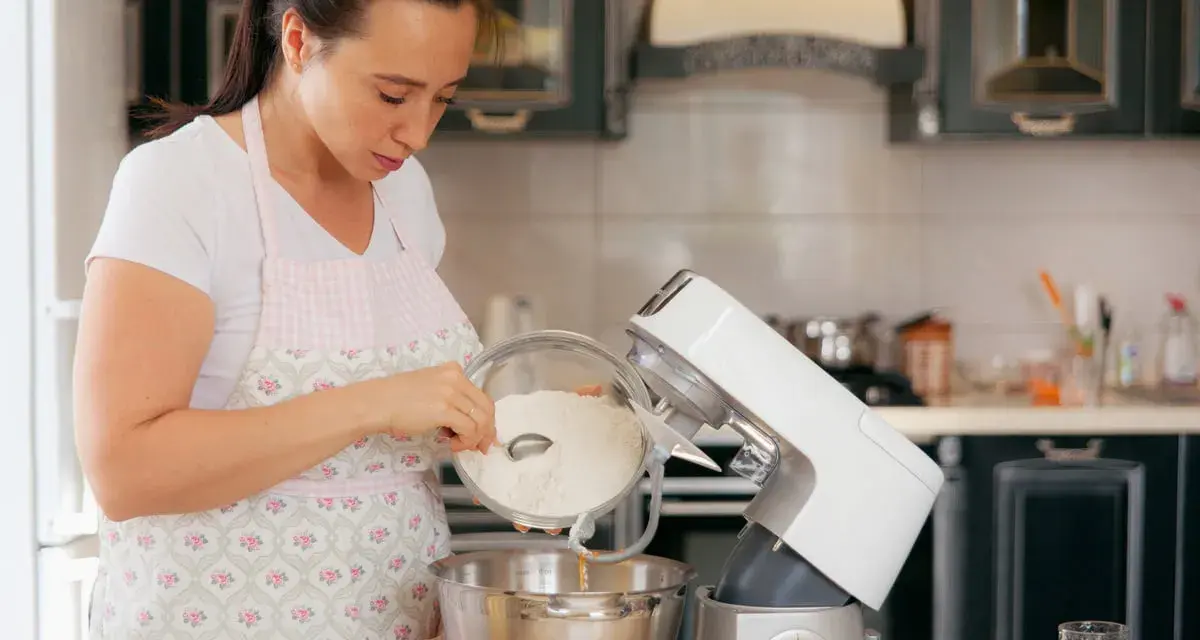 Une femme verse de la farine dans un robot pâtissier. Quel fouet pour pétrir !