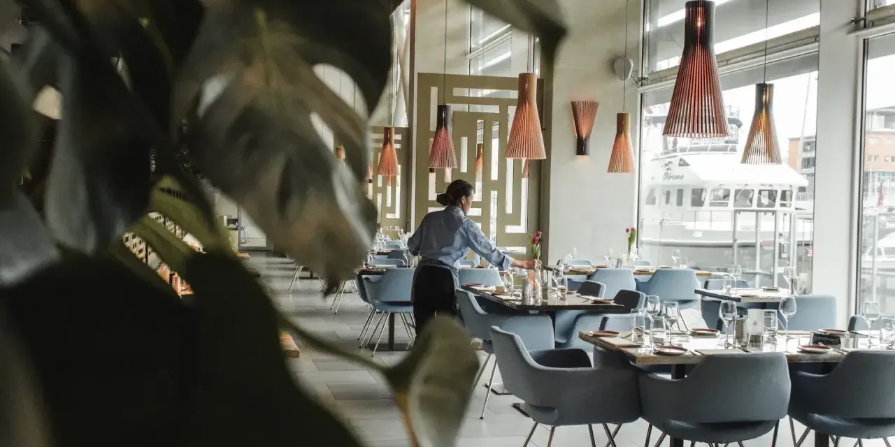 Serveuse préparant les tables dans un restaurant chic. Le 11 novembre est férié, mais ce restaurant est ouvert pour vous accueillir.