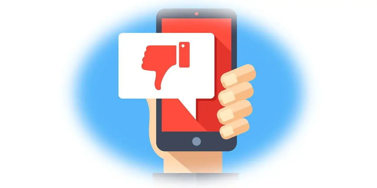 Main d'une personne tenant un smartphone affichant un pouce vers le bas dans une bulle de dialogue. Un mauvais avis sur un achat.