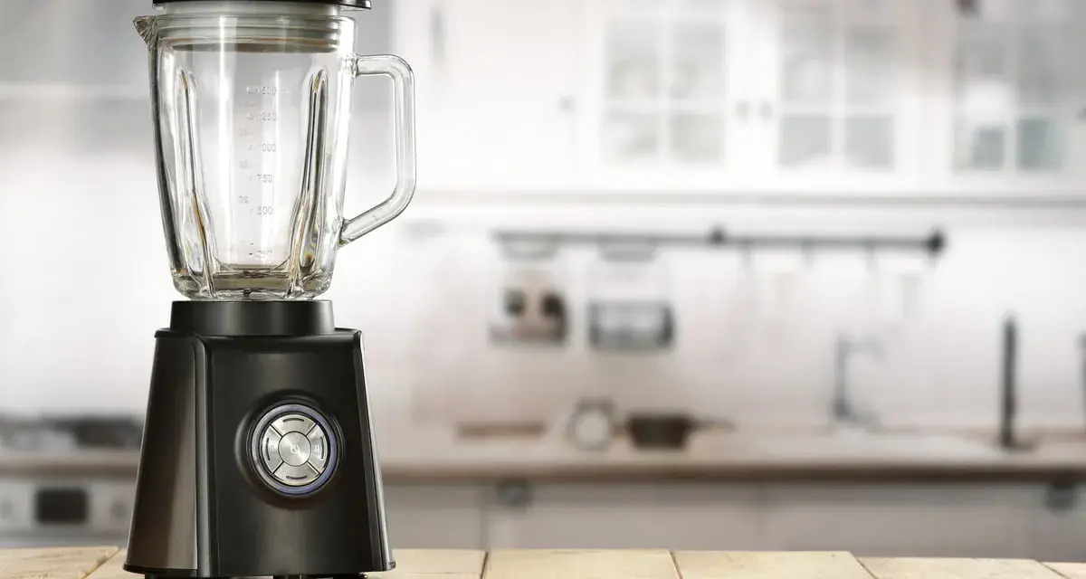 Blender noir sur table en bois. Peut-on hacher de la viande avec un blender ? Cet appareil est prêt à relever le défi.