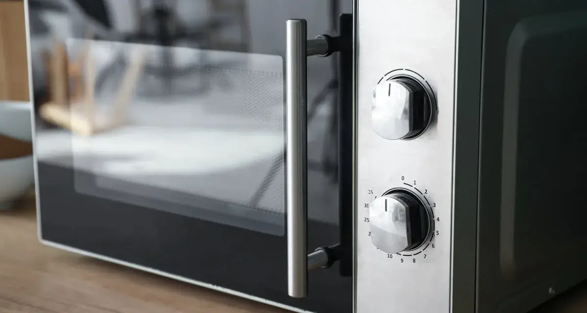 Gros plan sur un four micro-ondes avec deux boutons de réglage. Il est prêt à cuire, réchauffer ou décongeler, offrant le mode convection micro onde.