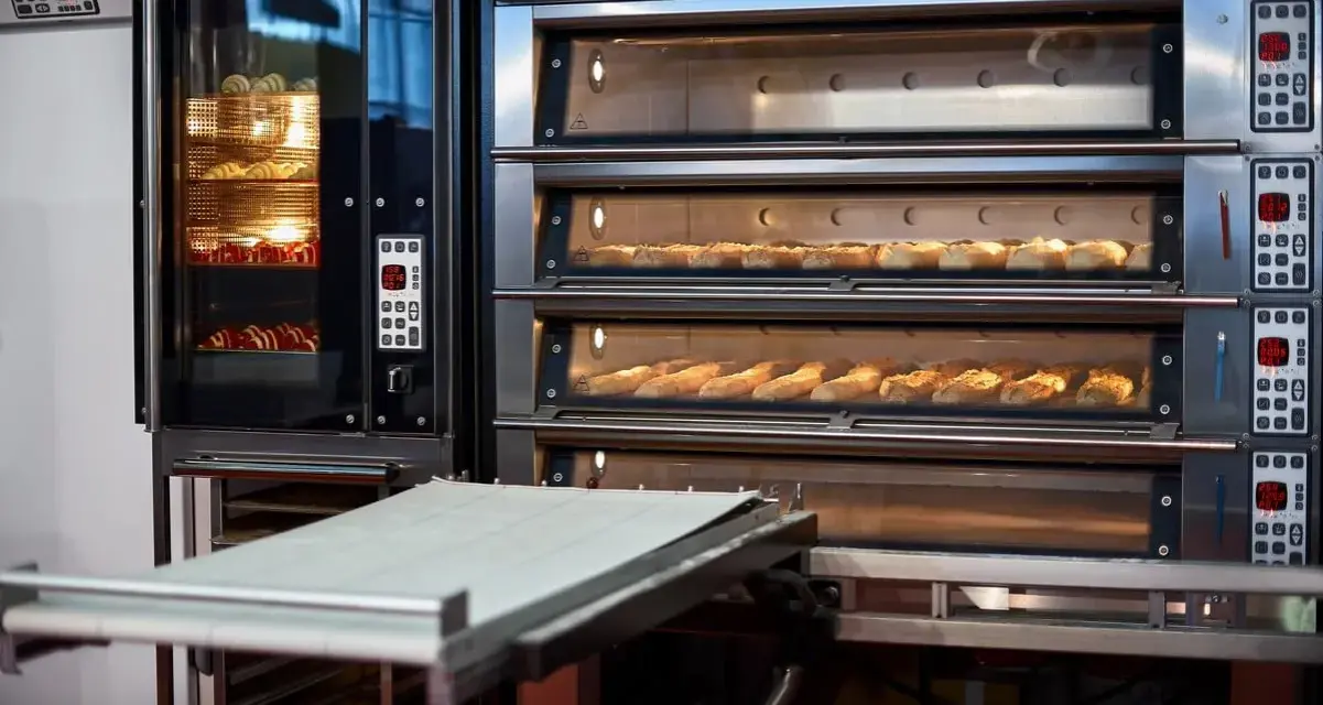Four à convection professionnel avec plusieurs étages de cuisson. Des pains dorés et des croissants attendent d'être dégustés.
