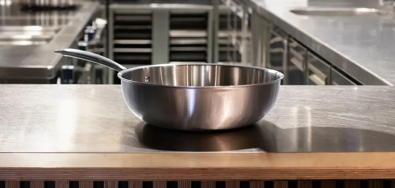Poêle en inox sur un plan de travail. Est-ce que l'inox va au four ? Oui, la plupart des ustensiles en inox sont adaptés au four.