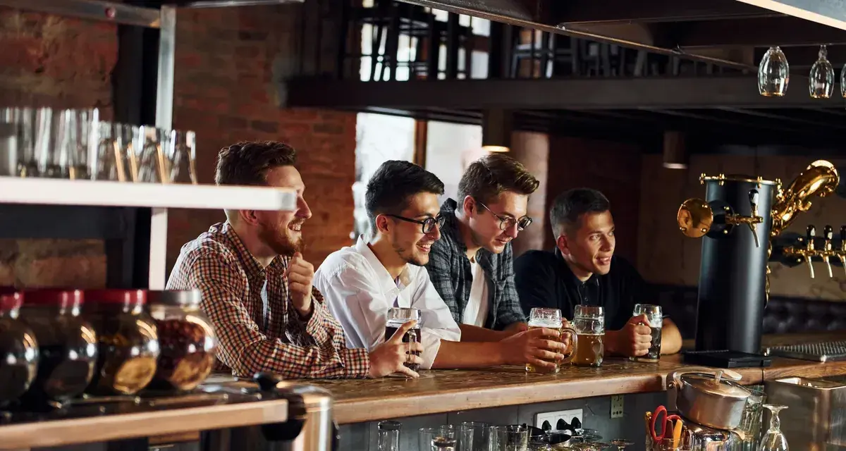 Quatre amis discutent et rient au bar, bières à la main. Le bruit de leur joie ne dérange personne, mais jusqu'à quelle heure un bar peut faire du bruit ?