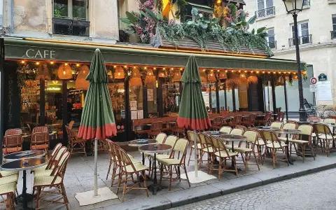 Terrasse de café parisien, tables et chaises en rotin, parasols verts. La réglementation terrasse sur trottoir est respectée.