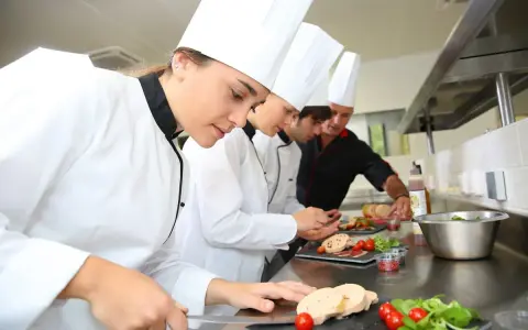 Des chefs apprennent à travailler dans un restaurant, préparant des plats avec soin.