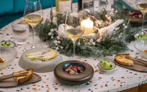Une table dressée pour une fete gastronomique, avec des verres de vin, des amuse-bouches et une décoration hivernale.