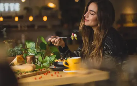Une femme savoure un plat de pâtes dans un restaurant. Son expression suggère un avis très positif sur le repas.