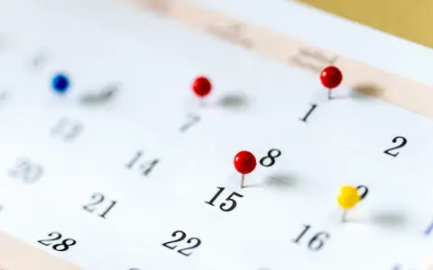 Un calendrier avec des punaises marque des dates importantes. Il est difficile de déterminer quels sont les 6 jours fériés garantis HCR sans plus de contexte.