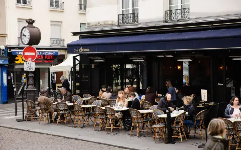 Terrasse animée d'un restaurant parisien, le Café Delmas, où des clients profitent de l'extérieur. Pas de tapage nocturne ici, juste une ambiance de bistrot paisible.
