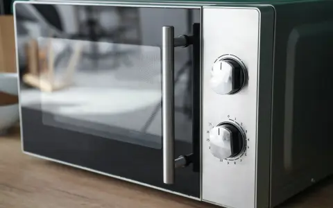 Gros plan sur un four micro-ondes avec deux boutons de réglage. Il est prêt à cuire, réchauffer ou décongeler, offrant le mode convection micro onde.