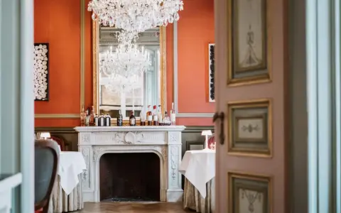 Salle à manger élégante avec cheminée, lustres et tables dressées. Un décor parfait pour savoir comment être référencé dans le Petit Futé.