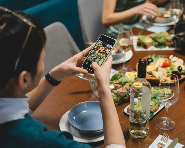 Une food influencer capture un repas coloré avec son téléphone, prête à partager ses découvertes culinaires.