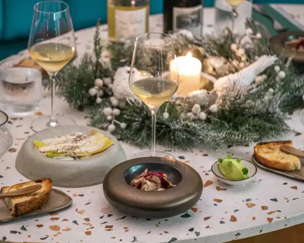 Une table dressée pour une fete gastronomique, avec des verres de vin, des amuse-bouches et une décoration hivernale.
