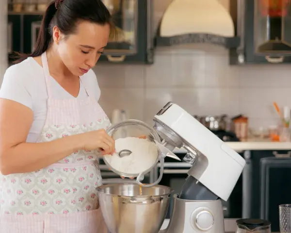 Une femme verse de la farine dans un robot pâtissier. Quel fouet pour pétrir !