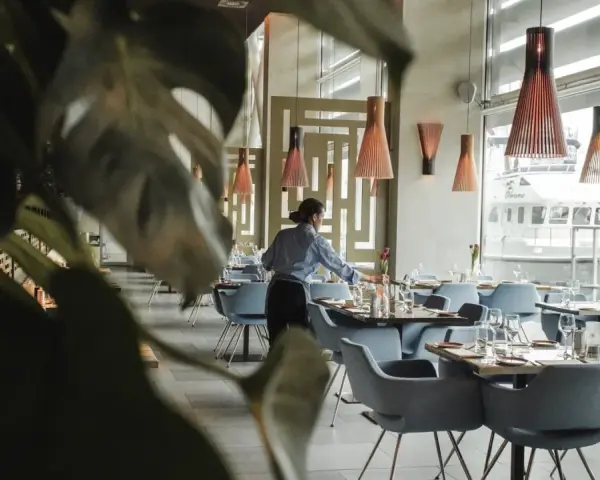 Serveuse préparant les tables dans un restaurant chic. Le 11 novembre est férié, mais ce restaurant est ouvert pour vous accueillir.