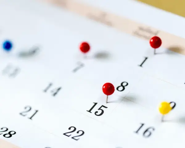 Un calendrier avec des punaises marque des dates importantes. Il est difficile de déterminer quels sont les 6 jours fériés garantis HCR sans plus de contexte.