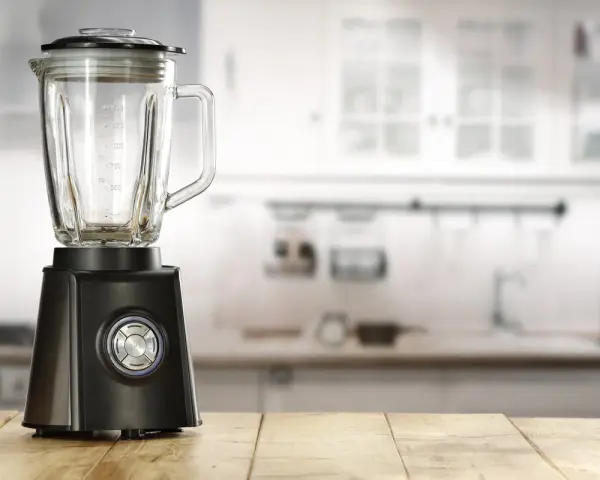 Blender noir sur table en bois. Peut-on hacher de la viande avec un blender ? Cet appareil est prêt à relever le défi.