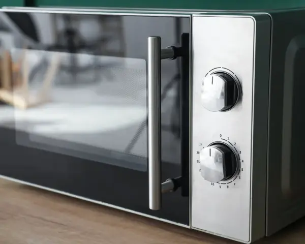 Gros plan sur un four micro-ondes avec deux boutons de réglage. Il est prêt à cuire, réchauffer ou décongeler, offrant le mode convection micro onde.