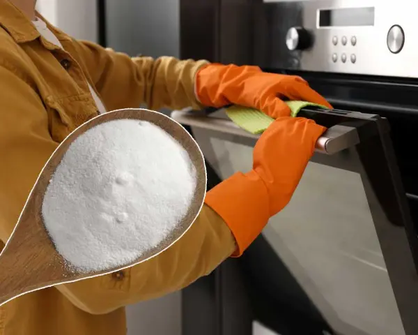 Une cuillère de bicarbonate de soude, le produit idéal avec quel produit nettoyer un four. Mains gantées nettoyant la porte du four.