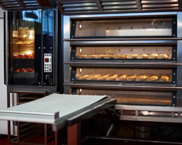 Four à convection professionnel avec plusieurs étages de cuisson. Des pains dorés et des croissants attendent d'être dégustés.