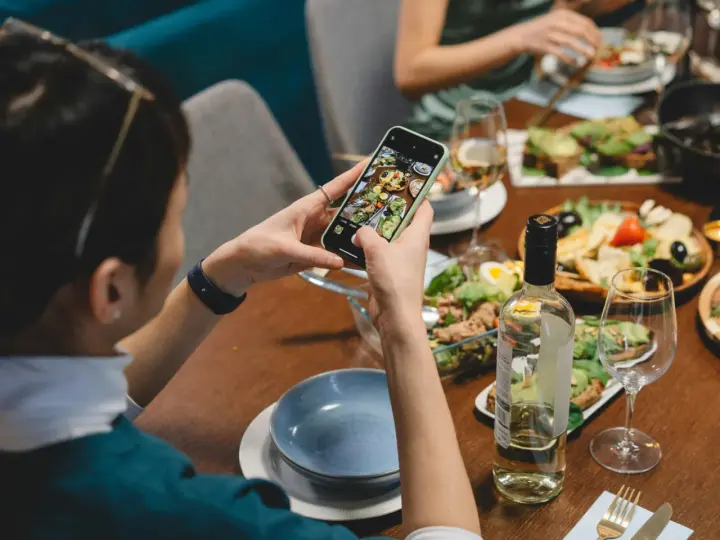 Une food influencer capture un repas coloré avec son téléphone, prête à partager ses découvertes culinaires.