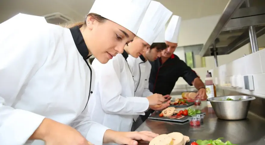 Des chefs apprennent à travailler dans un restaurant, préparant des plats avec soin.