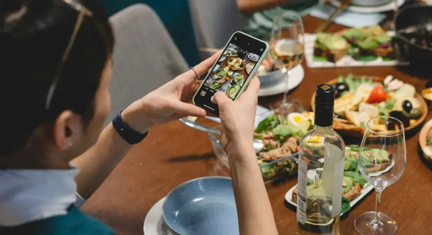 Une food influencer capture un repas coloré avec son téléphone, prête à partager ses découvertes culinaires.