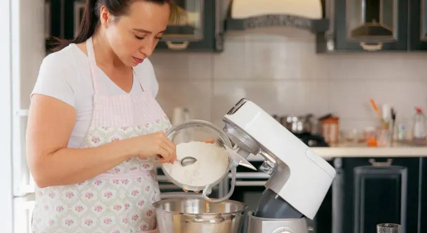 Une femme verse de la farine dans un robot pâtissier. Quel fouet pour pétrir !
