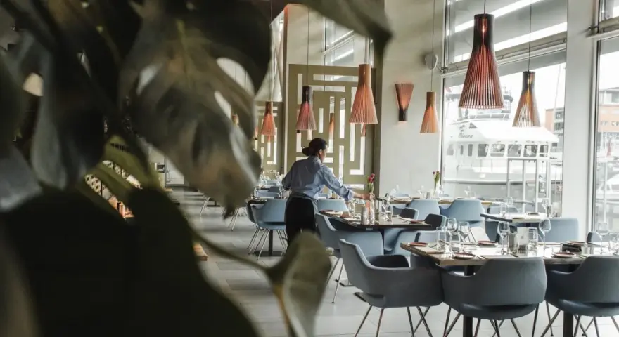 Serveuse préparant les tables dans un restaurant chic. Le 11 novembre est férié, mais ce restaurant est ouvert pour vous accueillir.