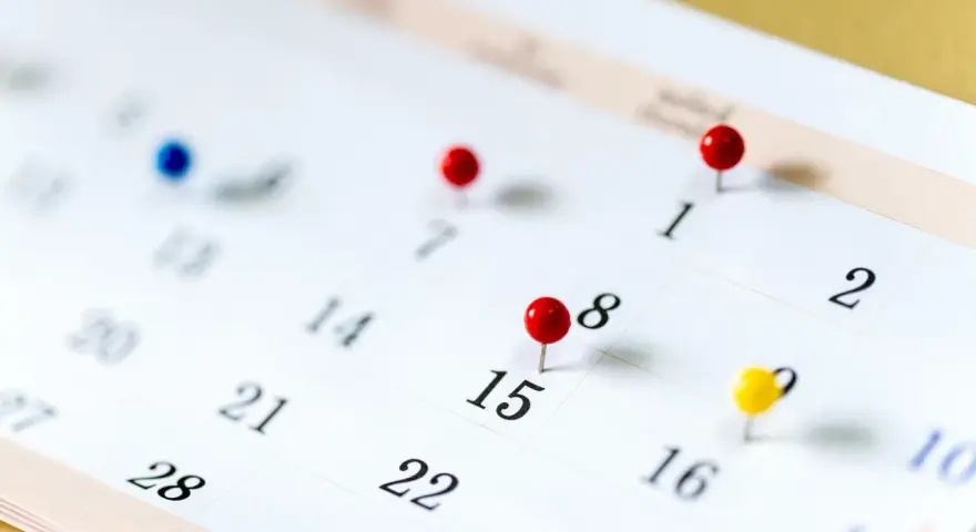 Un calendrier avec des punaises marque des dates importantes. Il est difficile de déterminer quels sont les 6 jours fériés garantis HCR sans plus de contexte.