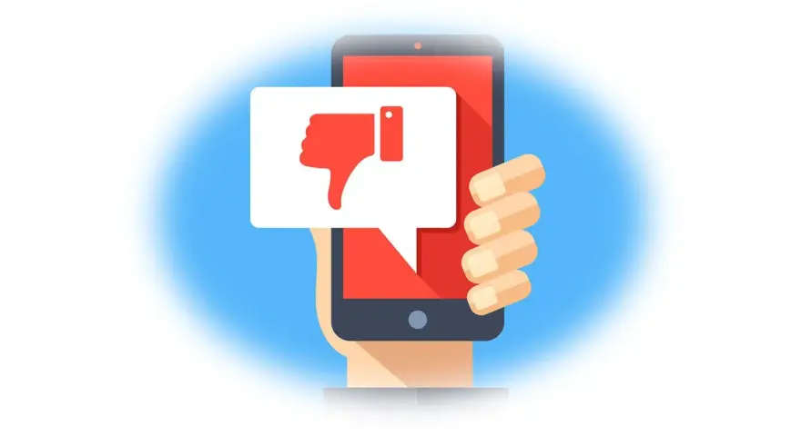 Main d'une personne tenant un smartphone affichant un pouce vers le bas dans une bulle de dialogue. Un mauvais avis sur un achat.