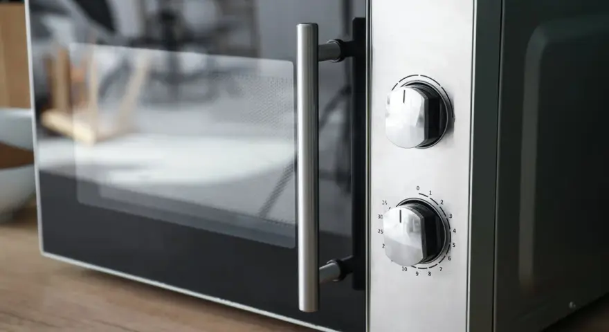 Gros plan sur un four micro-ondes avec deux boutons de réglage. Il est prêt à cuire, réchauffer ou décongeler, offrant le mode convection micro onde.