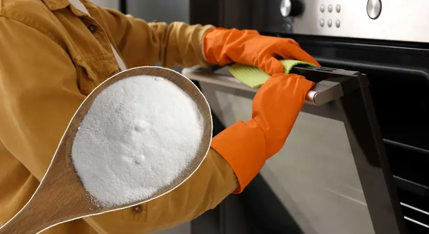 Une cuillère de bicarbonate de soude, le produit idéal avec quel produit nettoyer un four. Mains gantées nettoyant la porte du four.
