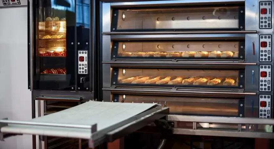 Four à convection professionnel avec plusieurs étages de cuisson. Des pains dorés et des croissants attendent d'être dégustés.